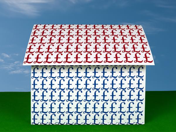 a house with Red pound signs decorating the roof and blue pound signs decorating the body of the house. Green grass and a blue sky in the background.