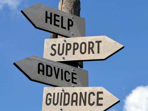 a blue sky with a wooden street sign, 4 arrows are nailed to the sign pointing in different directions saying 'HELP', 'SUPPORT', 'ADVICE', 'GUIDANCE'.