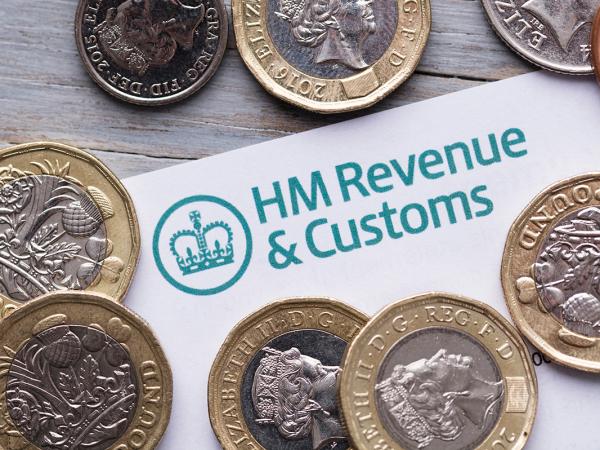 a letter from HMRC showing the logo in the top left corner, pound coins are scattered on top of the letter. 