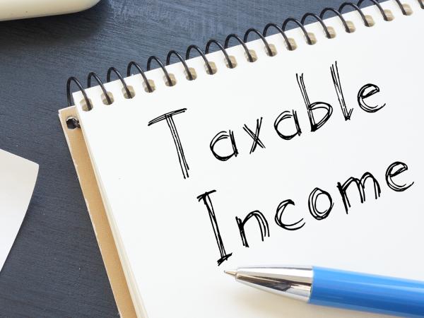 a drawing of a person holding money and a pad of paper with the words 'TAXABLE INCOME' written on it.