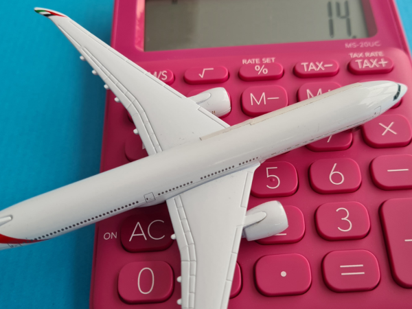A toy aeroplane sat on top of a red calculator. 