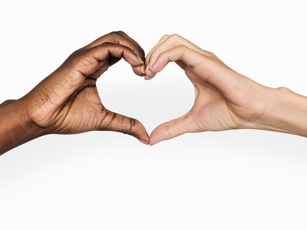 2 people holding hands out to one another, where their hands touch they are making the shape of a heart