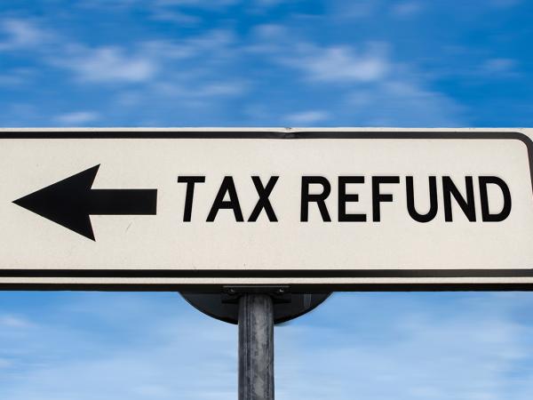 a blue sky background with a street sign saying 'TAX REFUND' 