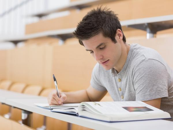 Young man reading / studying and making notes in a lecture hall. ©shutterstock/ESB Professional