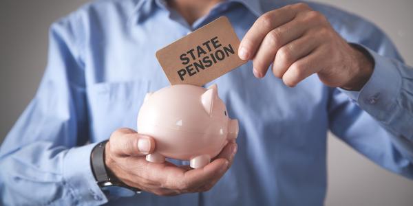 a person holding a piggy bank and inserting a card with the words 'STATE PENSION' into the piggy bank
