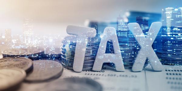 coins, the word tax, with a lit up city scene in the background.