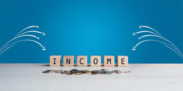Wooden blocks spelling out the word 'INCOME' against a blue background, white arrows are pointing towards the word.