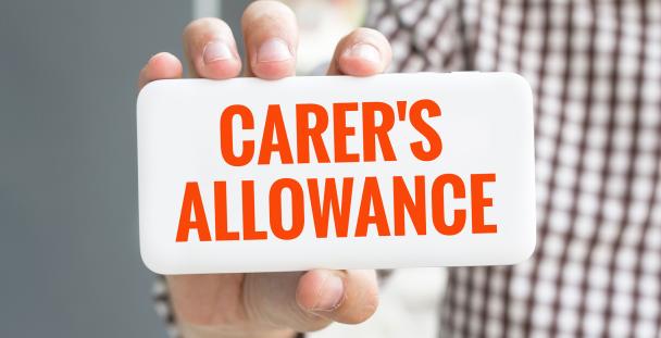 Image of a person hold a sign saying carer's allowance Image of a person hold a sign saying carer's allowance