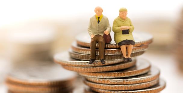 Image of models of pensioners sitting on a pile of coins Image of models of pensioners sitting on a pile of coins