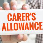 Image of a person hold a sign saying carer's allowance