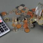 Image of a jar of coins with the word coronavirus on it next to a calculator