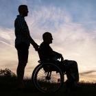 Image of the silhouette of a man pushing another man in a wheelchair