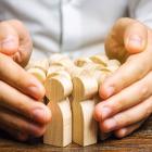 Image of a pair of hands surrounding wooden models of people illustrating job retention