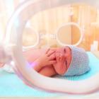 newborn baby lying inside the infant incubator in hospital