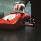 A hand reaching for a red telephone.