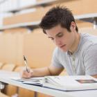 Young man reading / studying and making notes in a lecture hall. ©shutterstock/ESB Professional