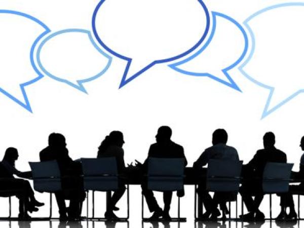 silhouette of people sat around a table with blue speech bubbles above their heads