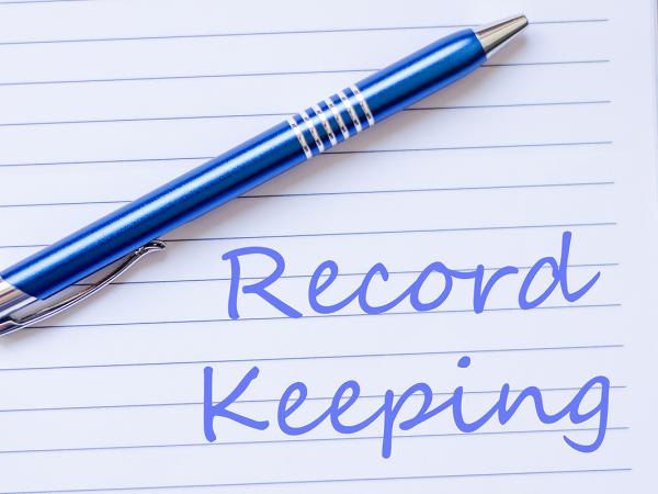 A pad of paper with a blue pen, written on the paper in blue ink are the words 'RECORD KEEPING'