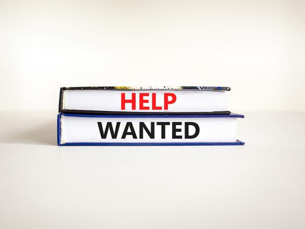 2 books against a neutral coloured background, on the side of the books the words 'HELP WANTED' is written in black and red.