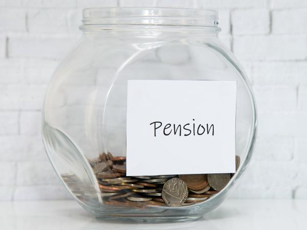 a glass jar with coins inside, on the jar is a handwritten sign saying 'PENSION' 