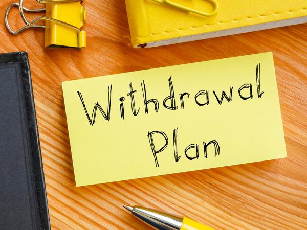 a post-it note on a desk with the words 'WITHDRAWAL PLAN' written on it.