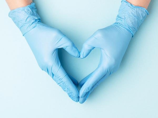 care workers hands wearing blue gloves and holding their hands to shape a heart