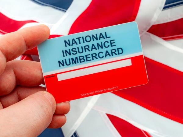 a person holding a 'national insurance numbercard' with a flag of The United Kingdom in the background