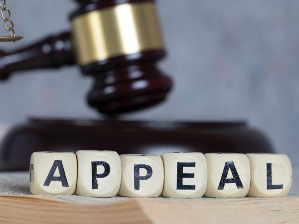 the word 'APPEAL' spelt out in white blocks, behind this a gavel can be seen and on the left a bronze coloured old fashioned weighing scale