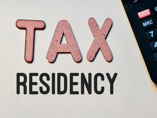 the word 'TAX' in red letters and the word 'RESIDENCY' in black letters next to a calculator