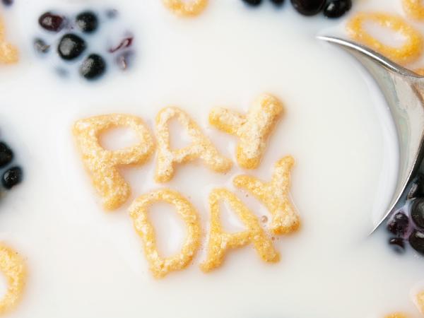 letters of cereal along with blackberries floating in Milk spelling out the words 'PAY DAY'