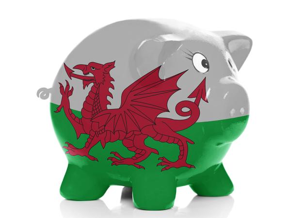 a ceramic piggy bank on a white background decorated with the Welsh flag