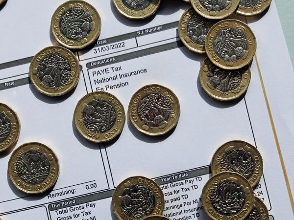 a pay slip showing 'National insurance contributions' scattered with British pound coins.