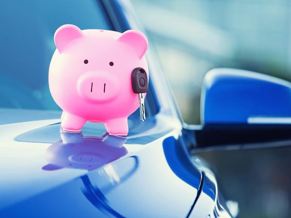 a blue car with a pink piggy bank and car key on the bonnet