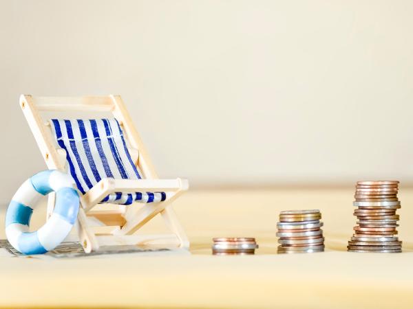 a beach chair, swim ring and stacks of coins on a makeshift beach. 