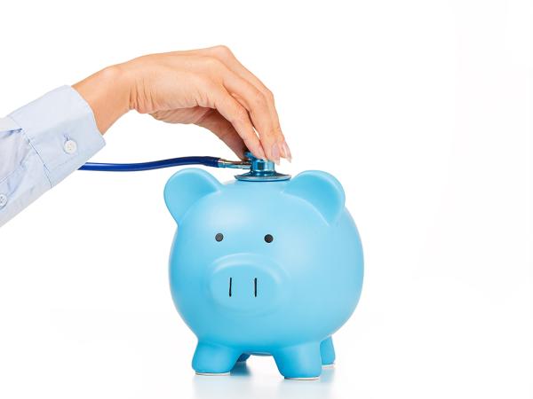 a person holding a stethoscope to a blue piggy bank. 