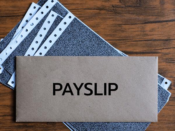 a stack of paper with an envelope on top, typed on the envelope is the word 'PAYSLIP' 