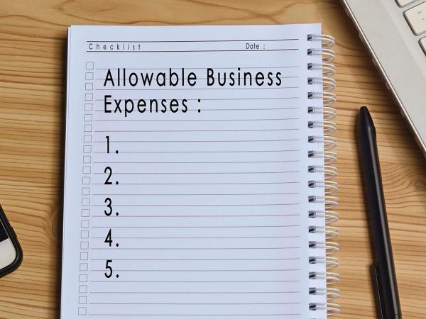 a desk with a pad of writing paper, written on the paper are the words ' ALLOWABLE BUSINESS EXPENSES' 