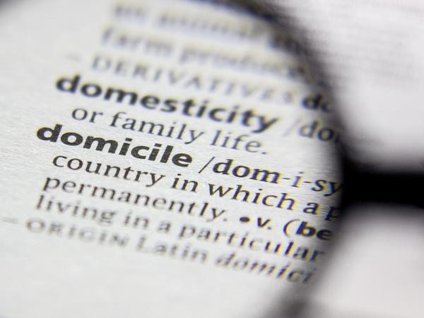The dictionay definition of 'DOMICILE' being looked at through a magnifying glass.