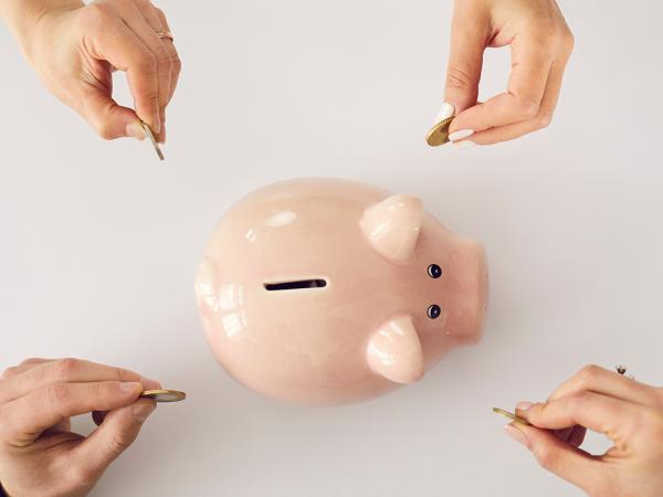 a piggy bank with four people putting coins inside