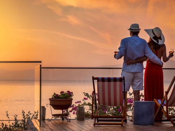 a couple looking out over a balcony at a sunset