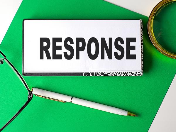 a notebook with the word 'RESPONSE' typed on it, a magnifying glass, a pen and a pair of glasses