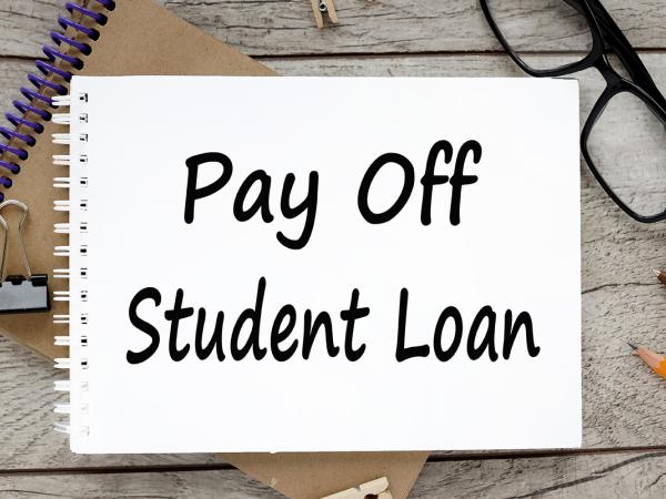 a notebook with the words 'PAY OFF STUDENT LOAN' written on it in black ink