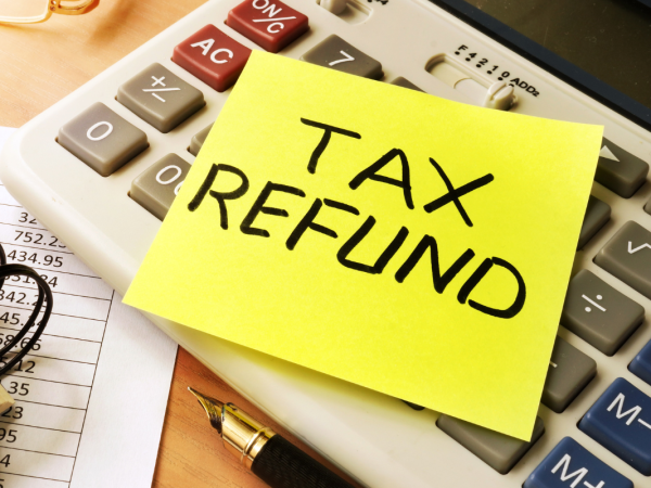 A notebook, a calculator and a note with the words 'TAX REFUND'. 