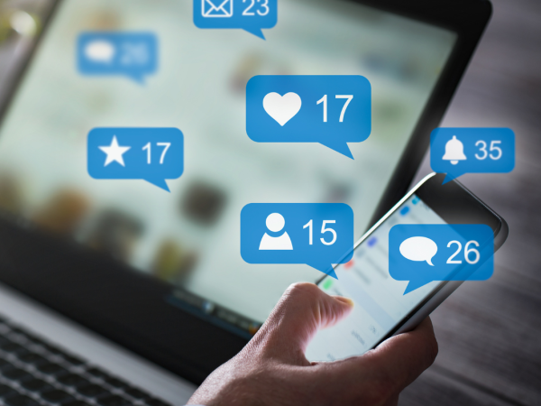 A laptop screen and phone screen with various different notifications from social media displayed. 