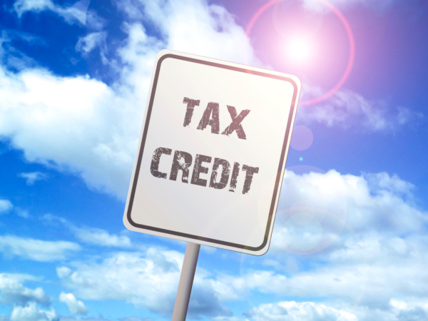A blue sky and a white road sign with the words 'TAX CREDITS'. 