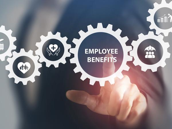 An employer pointing to a section of a hologram. the hologram shows many cogs interlinking, each with a different icon on the cog. The employer is pointing to the cog that says 'EMPLOYEE BENEFITS'. 