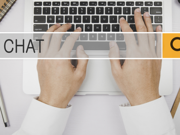 A person typing on a laptop, a translucent search box in front of the laptop with the word 'CHAT' written inside. 