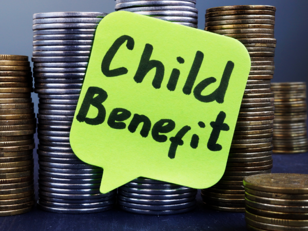Many stacks of coins with a yellow speech bubble that reads 'CHILD BENEFIT'. 