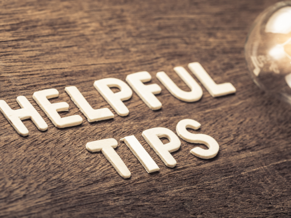 A wooden table with light coloured wooden letters spelling out the words 'HELPFUL TIPS' next to a lightbulb. 