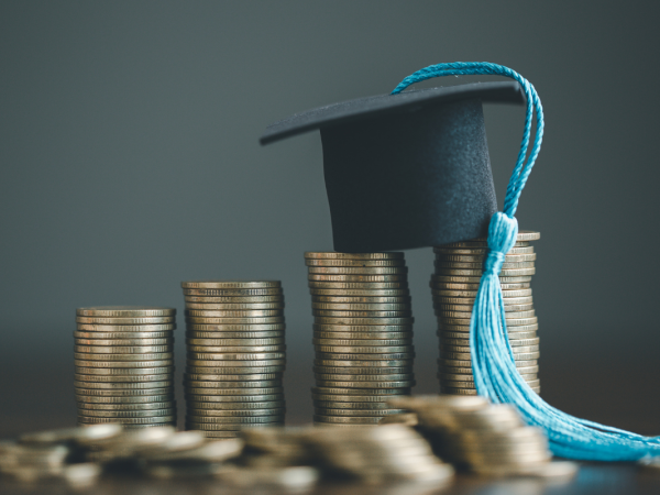 piles of coins with a graduation cap on top. 